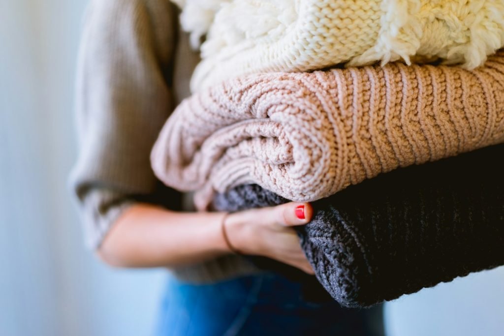 Hands holding a stack of soft folded knitwear